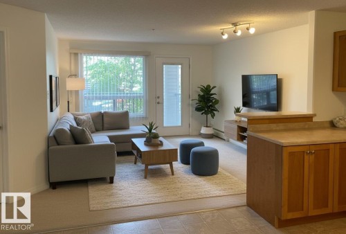 Bright living area featuring a large window, light-toned walls, and track lighting - #6201 7331 South Terwillegar Dr Nw, Edmonton, AB - Indoor Photo Showing Living Room