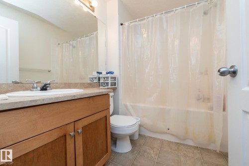 Bathroom featuring a light wood-finish vanity with an integrated sink, a light-colored countertop, and a vanity mirror - #6201 7331 South Terwillegar Dr Nw, Edmonton, AB - Indoor Photo Showing Bathroom