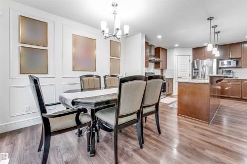Dining area featuring wood-finish flooring, wainscoting, and an open concept to the kitchen - 6727 20 Ave Sw, Edmonton, AB - Indoor Photo Showing Dining Room
