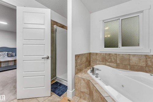 Bathroom featuring a built-in tub with tile surround, a separate shower enclosure, and a window with frosted glass - 6727 20 Ave Sw, Edmonton, AB - Indoor Photo Showing Bathroom