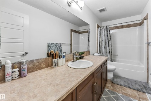 Bathroom featuring a single vanity with a laminate countertop, a full-width mirror, and dark wood-finish cabinetry - 6727 20 Ave Sw, Edmonton, AB - Indoor Photo Showing Bathroom