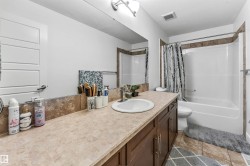 Bathroom featuring a single vanity with a laminate countertop, a full-width mirror, and dark wood-finish cabinetry - 