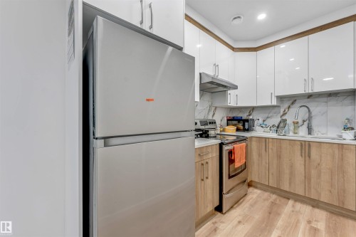Compact kitchen featuring a stainless steel refrigerator, range, and range hood - 6727 20 Ave Sw, Edmonton, AB - Indoor Photo Showing Kitchen