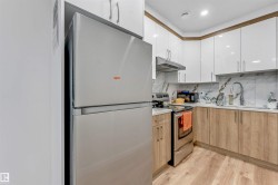 Compact kitchen featuring a stainless steel refrigerator, range, and range hood - 