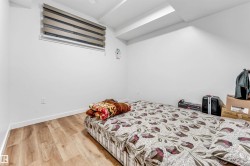Spacious room featuring wood-finish flooring, white baseboards, and bright white walls - 
