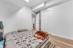 Bedroom featuring light wood-finish flooring, white walls, white baseboards, and bi-fold closet doors with panel detailing - 