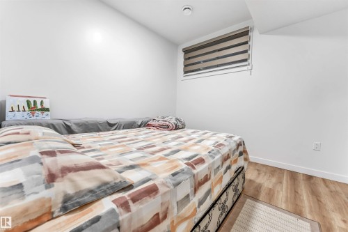 Room featuring light wood-finish flooring, white walls, and a window with horizontal blinds - 6727 20 Ave Sw, Edmonton, AB - Indoor Photo Showing Bedroom