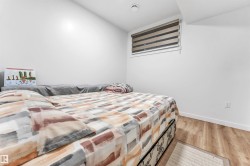 Room featuring light wood-finish flooring, white walls, and a window with horizontal blinds - 