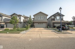 Two-story residential architecture featuring a gray siding exterior with stone accenting, a concrete driveway, and an integrated single-car garage - 