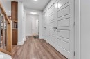 Hallway featuring wood-finish flooring, contemporary white interior doors, and a built-in wood-toned cabinet with a light-toned countertop - 6727 20 Ave Sw, Edmonton, AB  - Indoor Photo Showing Other Room 