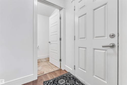 Panel-style door with brushed nickel hardware opening to a room with tiled flooring - 6727 20 Ave Sw, Edmonton, AB - Indoor Photo Showing Other Room