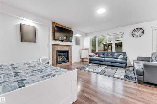Spacious interior featuring wood-finish flooring and white walls - 6727 20 Ave Sw, Edmonton, AB - Indoor Photo Showing Living Room With Fireplace