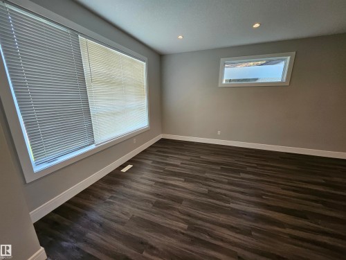 Spacious room featuring wood-finish flooring, two large windows with blinds, recessed ceiling lighting, and neutral wall paint - 9311 66 Avenue Nw, Edmonton, AB - Indoor Photo Showing Other Room
