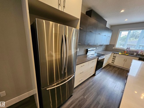 Modern kitchen featuring stainless steel appliances, dark wood-finish flooring, and two-tone cabinetry - 9311 66 Avenue Nw, Edmonton, AB - Indoor Photo Showing Kitchen