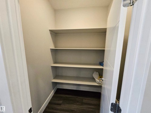 Pantry featuring multiple built-in shelving units, light-toned walls, and wood-finish flooring - 9311 66 Avenue Nw, Edmonton, AB - Indoor With Storage