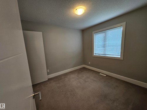 Bedroom featuring neutral wall paint, white trim, carpet flooring, and a single window with blinds - 9311 66 Avenue Nw, Edmonton, AB - Indoor Photo Showing Other Room