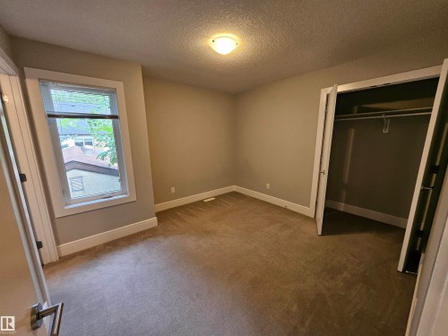 Carpeted room featuring a double-door closet, a single window with blinds, a ceiling-mounted light fixture, and white baseboards - 9311 66 Avenue Nw, Edmonton, AB - Indoor Photo Showing Other Room