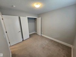 Carpeted room featuring a ceiling-mounted light fixture, neutral wall paint, white trim, and a bi-fold closet with shelving and a hanging rod - 
