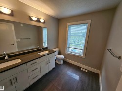 Bathroom featuring a dual vanity with white cabinetry, dark countertop, and integrated sinks - 