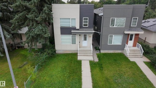 Modern multi-level exterior with a split facade in light and dark gray tones, white entry door, multiple windows, concrete steps, and a compact front lawn - 9311 66 Avenue Nw, Edmonton, AB - Outdoor With Facade