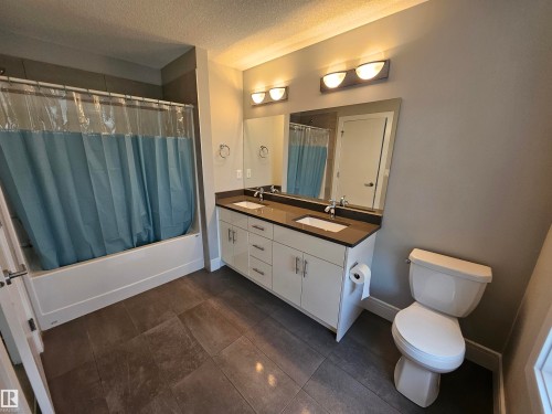 Bathroom featuring a double vanity with stone countertops, individual mirrors, and modern light fixtures - 9311 66 Avenue Nw, Edmonton, AB - Indoor Photo Showing Bathroom