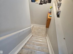 Interior staircase with light grey walls, white baseboards, and a white handrail - 