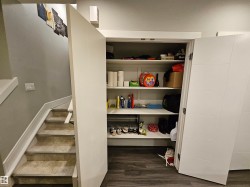 Built-in storage closet featuring white shelving and white paneled doors - 