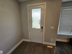 Entryway featuring a white door with decorative glass, wood-finish flooring, and light gray wall paint - 