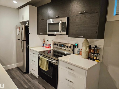 Modern kitchen featuring white and dark wood-finish cabinetry - 9311 66 Avenue Nw, Edmonton, AB - Indoor Photo Showing Kitchen