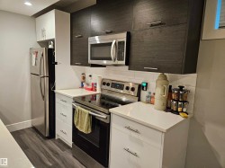 Modern kitchen featuring white and dark wood-finish cabinetry - 