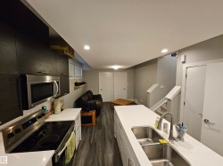 Modern kitchen with dark wood-finish cabinetry, stainless steel appliances, and a double basin sink - 