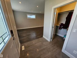 Tiled entry with a built-in closet featuring shelving and a hanging rod, leading to a room with wood-finish flooring, a rectangular window, and recessed lighting - 