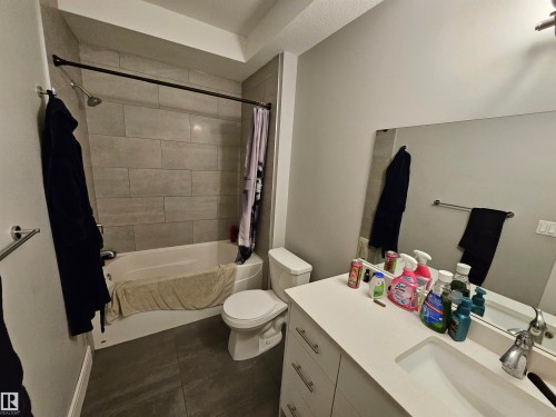 Full bathroom featuring a white tub, light gray subway-tiled shower surround, dark gray large-format floor tiles, a white vanity with an integrated sink, and a large wall-mounted mirror - 9311 66 Avenue Nw, Edmonton, AB - Indoor Photo Showing Bathroom