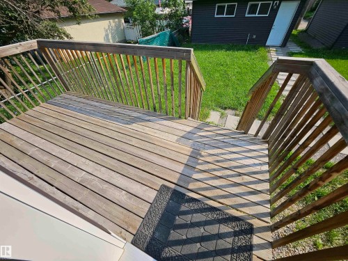 Spacious wooden deck with slatted railings and stairs descending to a green lawn - 9311 66 Avenue Nw, Edmonton, AB - Outdoor With Exterior
