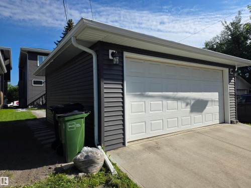 Detached garage with horizontal dark siding, white panel garage door, white gutters, and a concrete driveway - 9311 66 Avenue Nw, Edmonton, AB - Outdoor