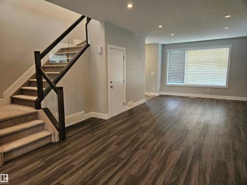 Spacious room featuring wood-finish flooring, recessed lighting, and a large window with blinds - 9311 66 Avenue Nw, Edmonton, AB - Indoor Photo Showing Other Room
