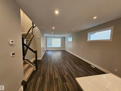 Open-concept living area featuring wood-finish flooring, recessed lighting, and neutral wall tones - 9311 66 Avenue Nw, Edmonton, AB - Indoor Photo Showing Other Room