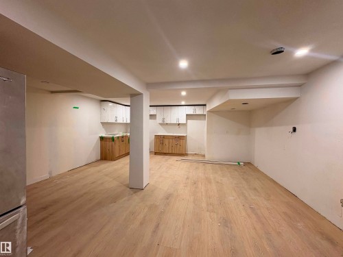 Open-concept space featuring wood-finish flooring, white walls, recessed lighting, and a partial kitchen area with light wood-finish base cabinetry and white upper cabinets - 18007 73 Avenue Nw, Edmonton, AB - Indoor
