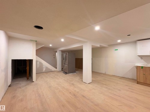 Spacious open-concept area featuring wood-finish flooring, recessed lighting, and a partially installed kitchen with light wood cabinetry and white upper cabinets - 18007 73 Avenue Nw, Edmonton, AB - Indoor