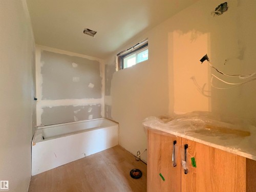 Bathroom under construction featuring a built-in bathtub, light wood-finish flooring, and a vanity cabinet with stone countertop - 18007 73 Avenue Nw, Edmonton, AB - Indoor Photo Showing Other Room