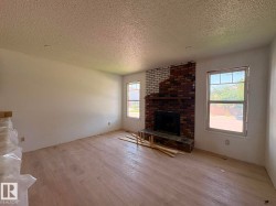 Interior space featuring a brick fireplace with a wood mantel, light wood-finish flooring, and white painted walls - 