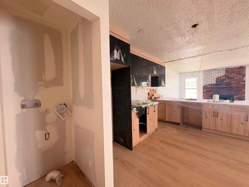Open concept interior featuring new wood-finish flooring, light wood cabinetry, and a brick fireplace - 18007 73 Avenue Nw, Edmonton, AB - Indoor