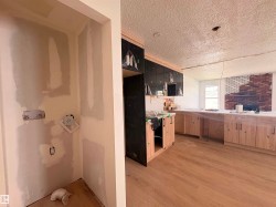 Open concept interior featuring new wood-finish flooring, light wood cabinetry, and a brick fireplace - 