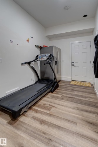 Light wood-finish flooring extending throughout the space - #8 1703 16 Av Nw Nw, Edmonton, AB - Indoor Photo Showing Gym Room