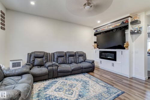 Integrated entertainment center featuring an electric fireplace, recessed lighting, and built-in white cabinetry - #8 1703 16 Av Nw Nw, Edmonton, AB - Indoor Photo Showing Living Room