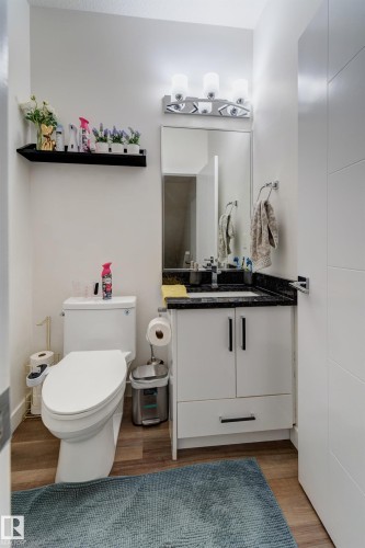 Bathroom featuring a white vanity with black hardware, a dark stone countertop, and an integrated sink with a chrome faucet - #8 1703 16 Av Nw Nw, Edmonton, AB - Indoor Photo Showing Bathroom
