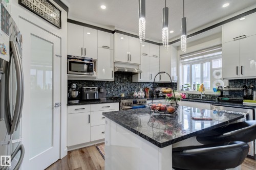 Contemporary kitchen featuring white high-gloss cabinetry and a dark mosaic tile backsplash - #8 1703 16 Av Nw Nw, Edmonton, AB - Indoor Photo Showing Kitchen With Upgraded Kitchen