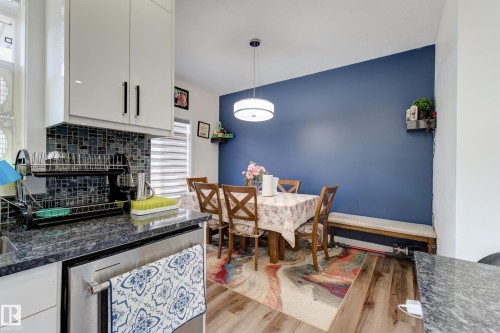 Kitchen and dining area featuring a blue accent wall and wood-finish flooring - #8 1703 16 Av Nw Nw, Edmonton, AB - Indoor Photo Showing Dining Room