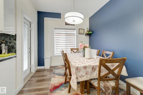 Dining area featuring wood-finish flooring, a contemporary drum pendant light, and a blue accent wall - #8 1703 16 Av Nw Nw, Edmonton, AB - Indoor Photo Showing Dining Room