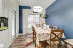 Dining area featuring wood-finish flooring, a contemporary drum pendant light, and a blue accent wall - 